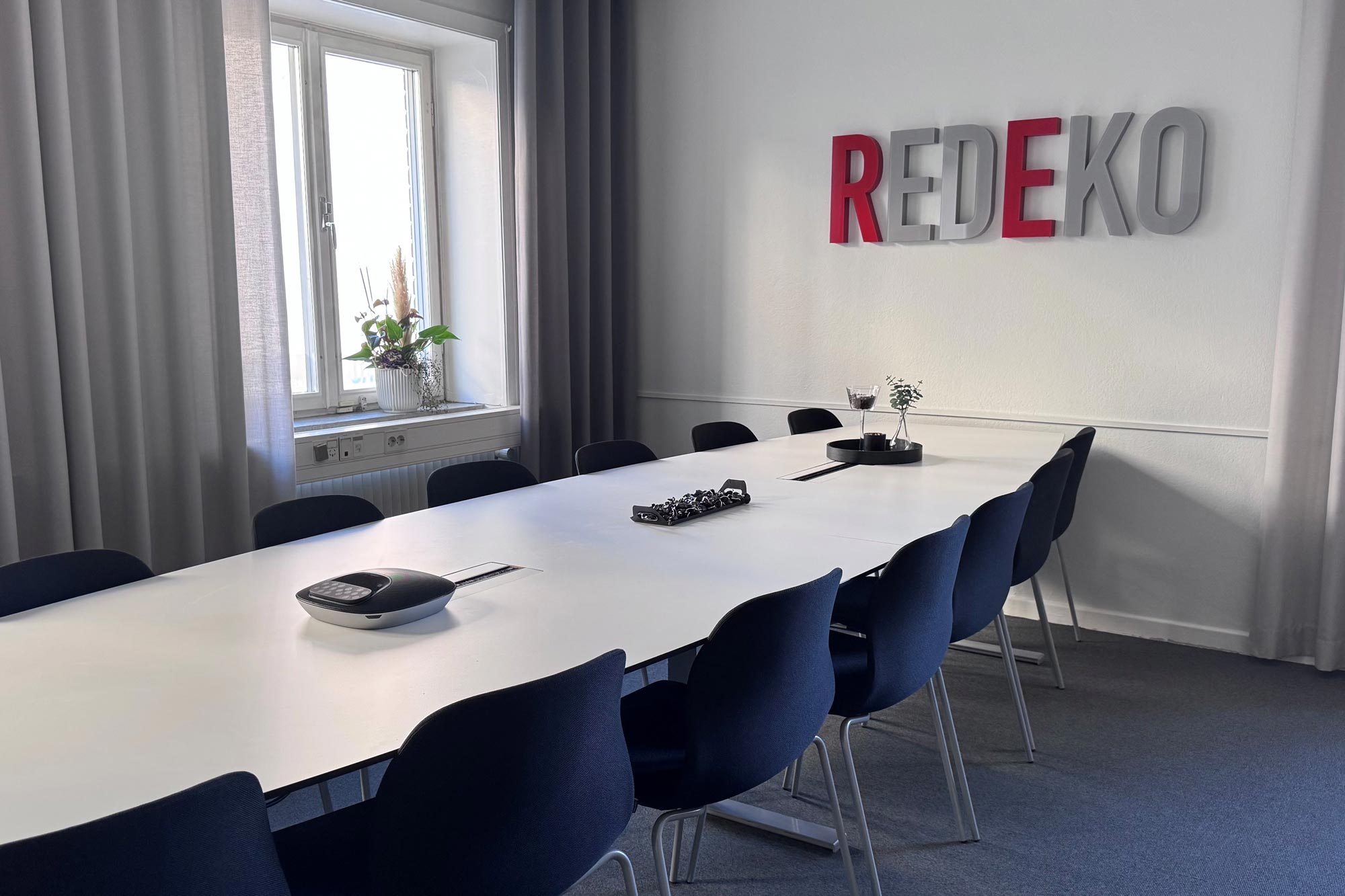 Modernt kontorsutrymme hos Redekos kontor med företagets logotyp synlig på väggen