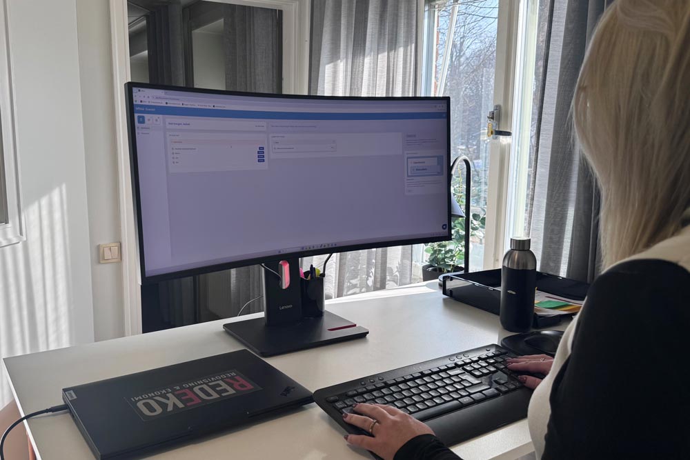 Kvinnlig medarbetare arbetar med ekonomiarbete vid dator på Redekos kontor