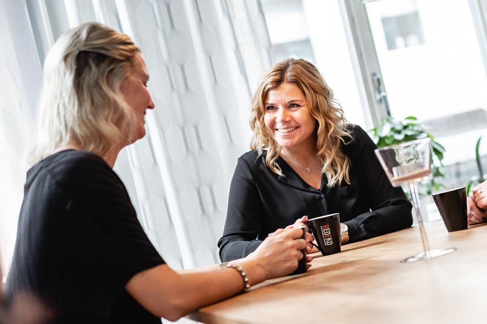 Två kvinnliga medarbetare sitter tillsammans och umgås på Redekos kontor